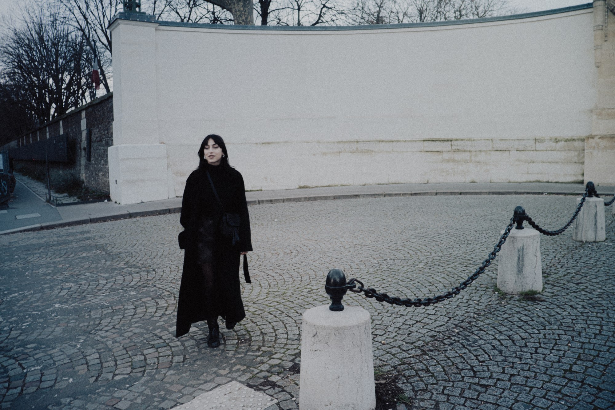Femme en manteau noir sur un pav&eacute; parisien