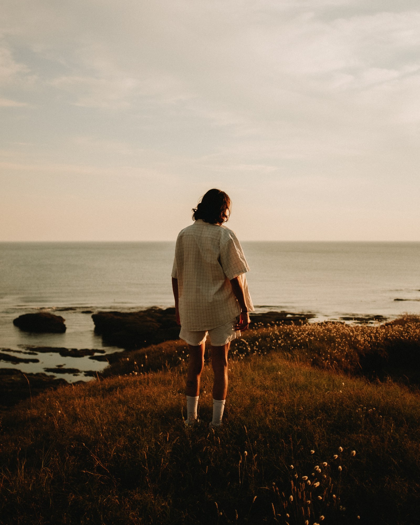 Femme face &agrave; la mer, falaises et lumi&egrave;re chaude