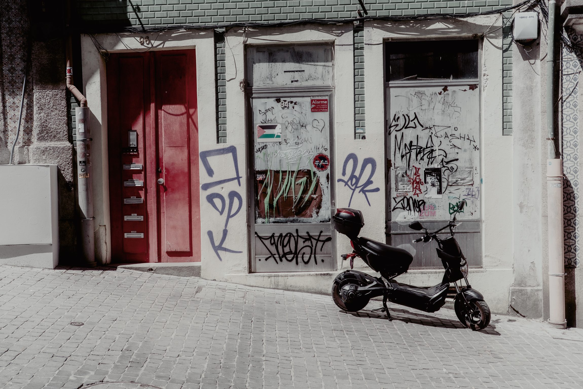 Porte rouge et graffitis, scooter gar&eacute; dans la rue