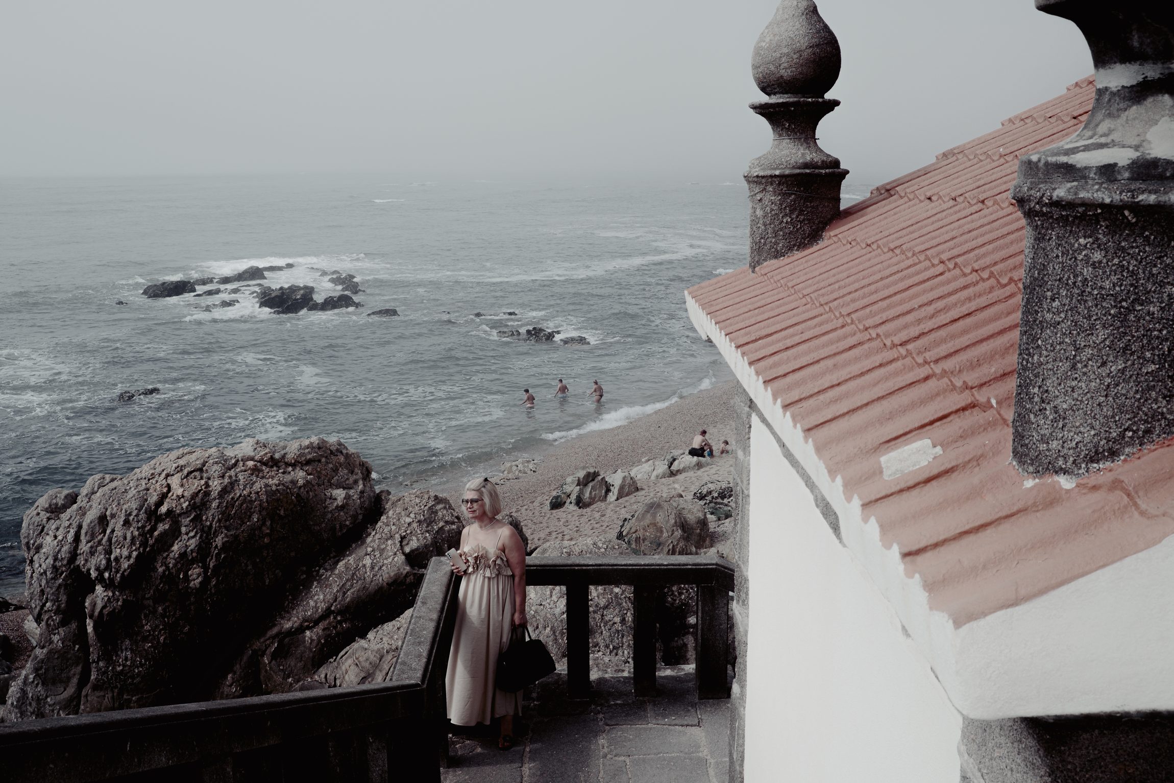 Femme sur un balcon face &agrave; la mer, toiture en tuiles rouges